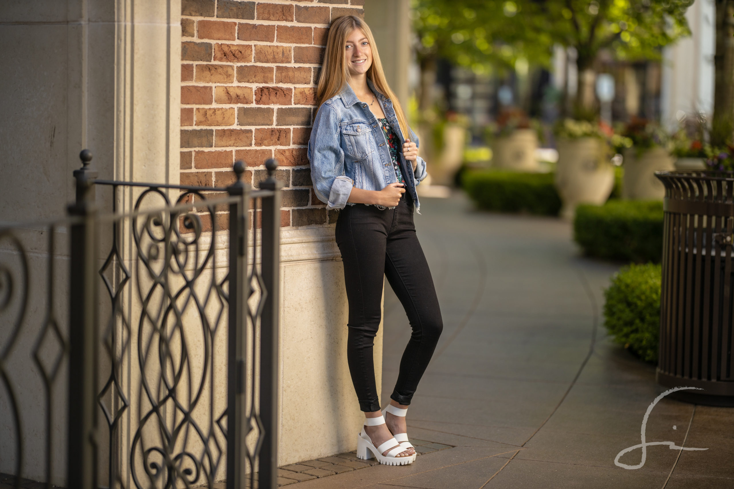 teen girl in black skinny jeans, a crop top, and a jean jacket leaning against a wall