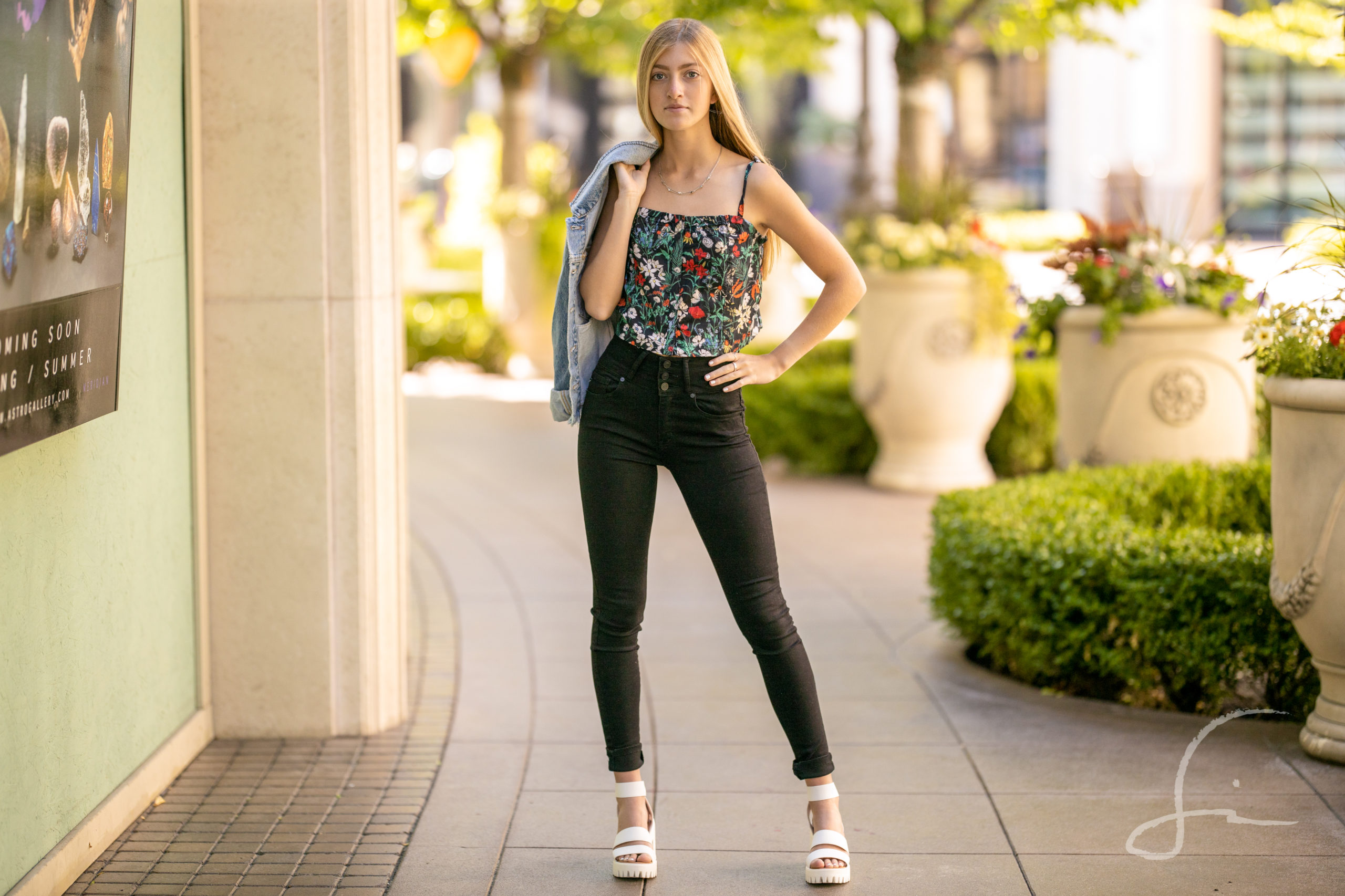 senior girl in a floral crop top and skinny jeans