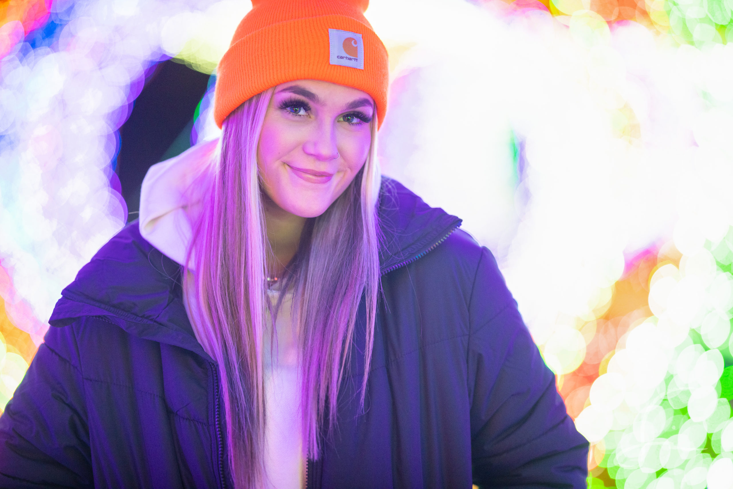 senior girl portrait in twinkle lights wearing a jacket and beanie hat