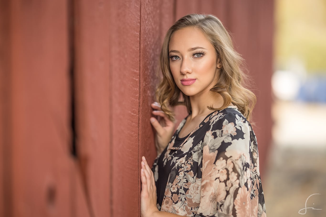 high school senior girl from captial high in boise idaho against a red wood barn in hidden springs idaho